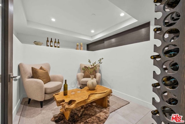 sitting room featuring a raised ceiling and light tile patterned floors