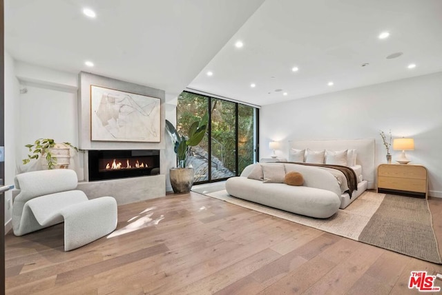 bedroom featuring access to outside, light hardwood / wood-style flooring, and a wall of windows