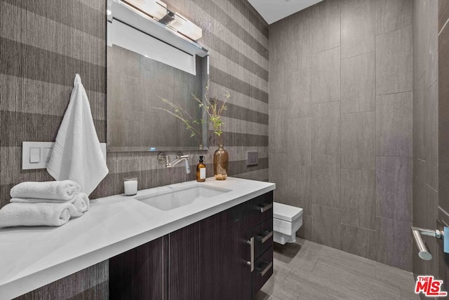 bathroom with tile patterned flooring, vanity, tile walls, and toilet