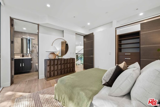 bedroom with ensuite bathroom, a closet, and light wood-type flooring