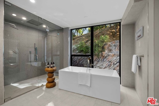 bathroom featuring tile patterned flooring, shower with separate bathtub, and tile walls