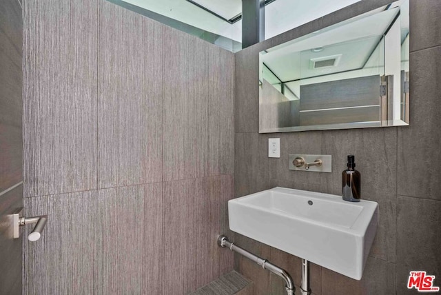 bathroom with sink and tile walls