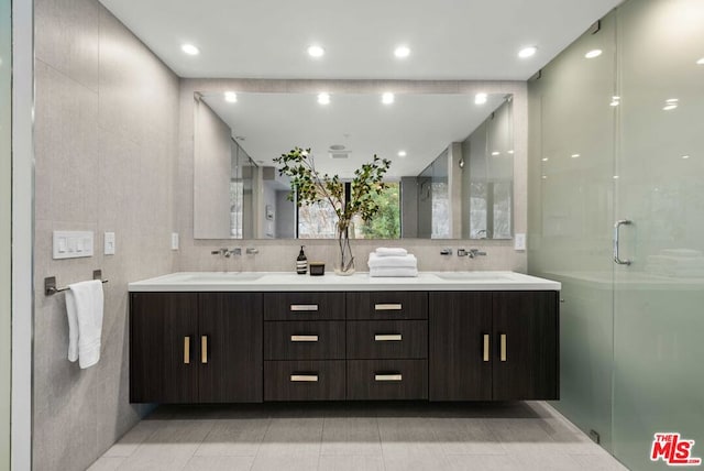 bathroom featuring tile patterned floors, a shower with door, vanity, and tile walls