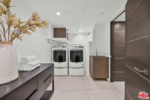 washroom featuring washer and clothes dryer, light tile patterned flooring, cabinets, and sink