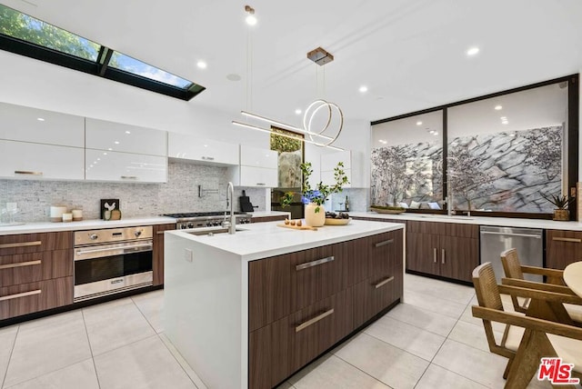 kitchen with tasteful backsplash, white cabinets, decorative light fixtures, light tile patterned floors, and appliances with stainless steel finishes