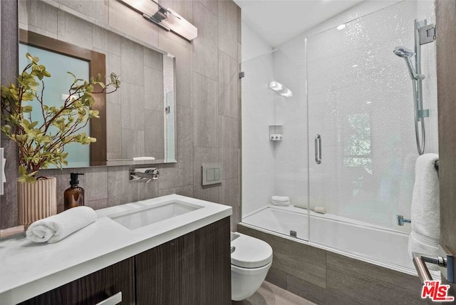 full bathroom with vanity, enclosed tub / shower combo, tile walls, and toilet