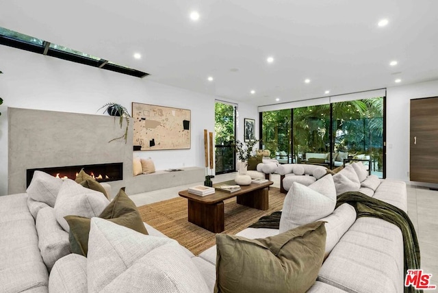 living room with light tile patterned flooring, a wall of windows, and a fireplace