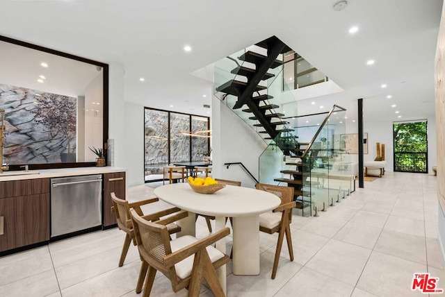 dining space with sink, light tile patterned floors, and a wall of windows