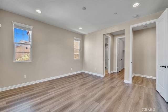 unfurnished bedroom with multiple windows, a closet, and light wood-type flooring