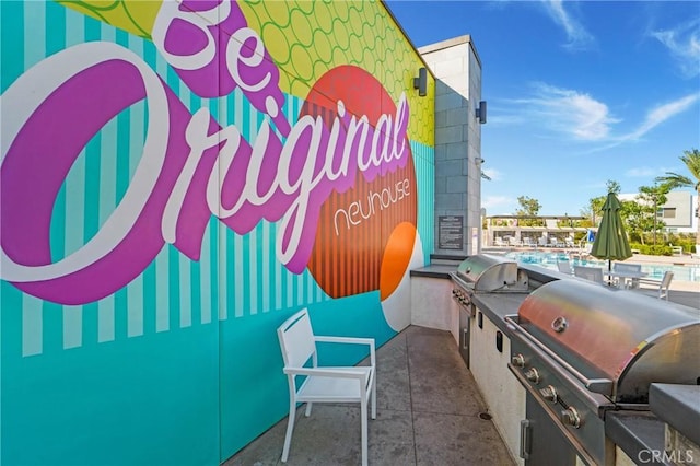 view of patio featuring grilling area, a community pool, and exterior kitchen