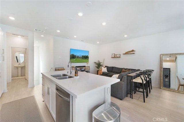 kitchen with sink, light hardwood / wood-style flooring, stainless steel dishwasher, a center island with sink, and white cabinets