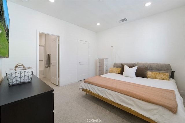 carpeted bedroom with ensuite bath and a closet