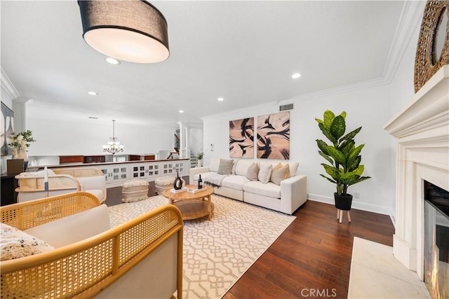 living room featuring dark hardwood / wood-style floors, crown molding, and a notable chandelier