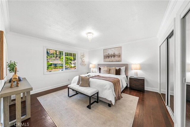 bedroom with a textured ceiling, dark hardwood / wood-style flooring, a closet, and ornamental molding