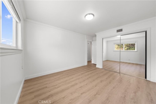 unfurnished bedroom with a closet, light hardwood / wood-style flooring, and crown molding