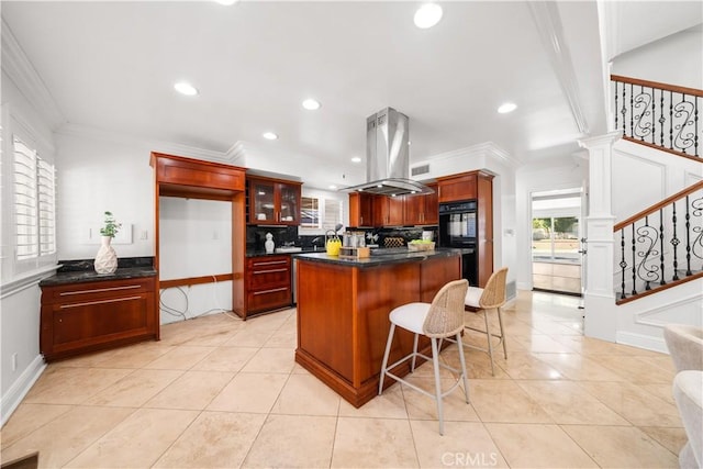 kitchen with island exhaust hood, black double oven, decorative backsplash, a kitchen island, and ornamental molding