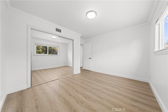 unfurnished bedroom featuring a closet, multiple windows, and light hardwood / wood-style floors