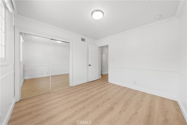 unfurnished bedroom featuring a closet, ornamental molding, and light hardwood / wood-style flooring