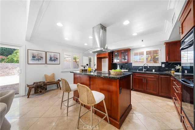 kitchen featuring tasteful backsplash, island exhaust hood, a kitchen island, and a healthy amount of sunlight