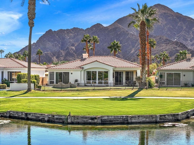 rear view of house featuring a lawn and a water and mountain view