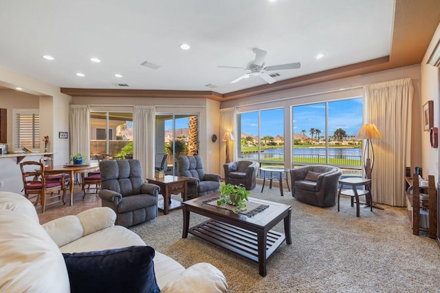 living room featuring a water view, carpet floors, a wealth of natural light, and ceiling fan