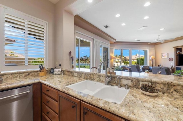 kitchen with ceiling fan, dishwasher, light stone counters, and sink