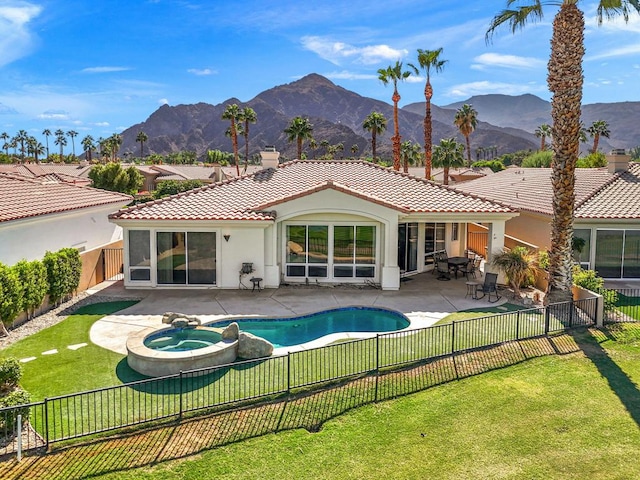 rear view of house with a mountain view, a yard, a patio area, and a pool with hot tub