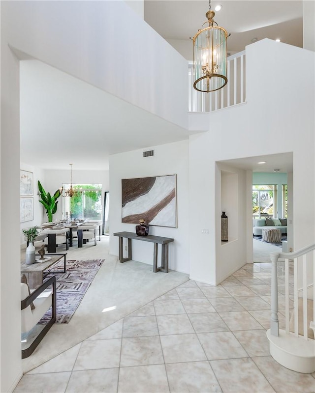 tiled entryway with a chandelier and a high ceiling