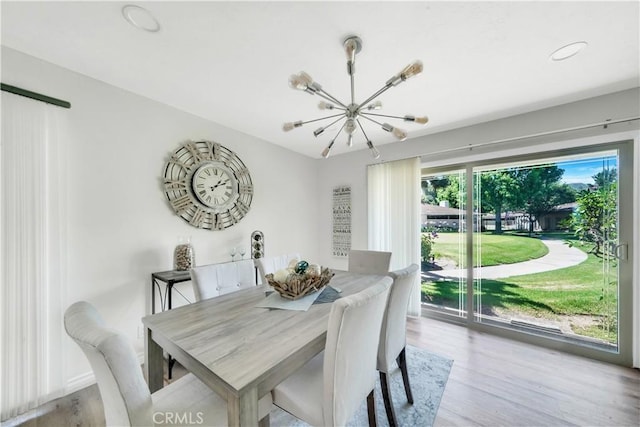 dining space with wood finished floors and a notable chandelier