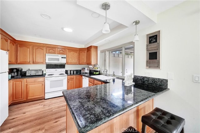 kitchen with pendant lighting, white appliances, sink, light hardwood / wood-style floors, and kitchen peninsula