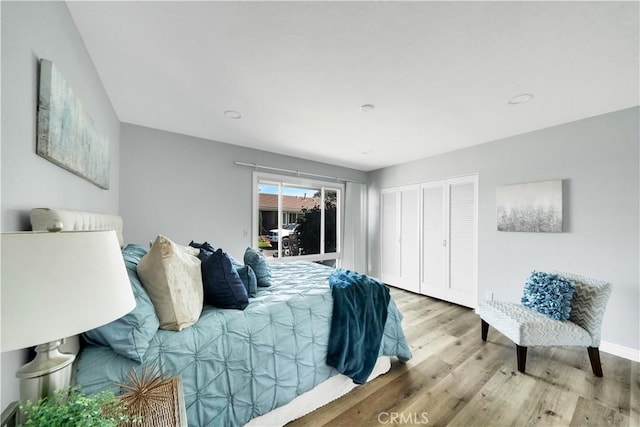 bedroom with access to outside, a closet, wood finished floors, and baseboards