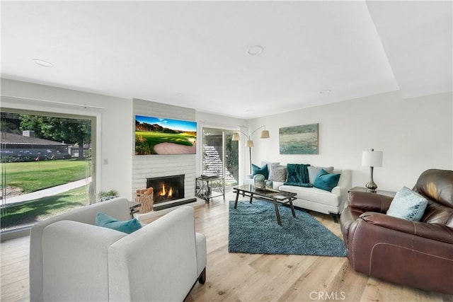 living room featuring a brick fireplace and light wood-type flooring