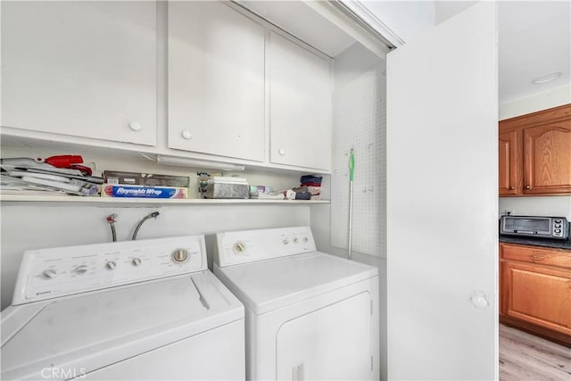 laundry room with separate washer and dryer and light hardwood / wood-style floors