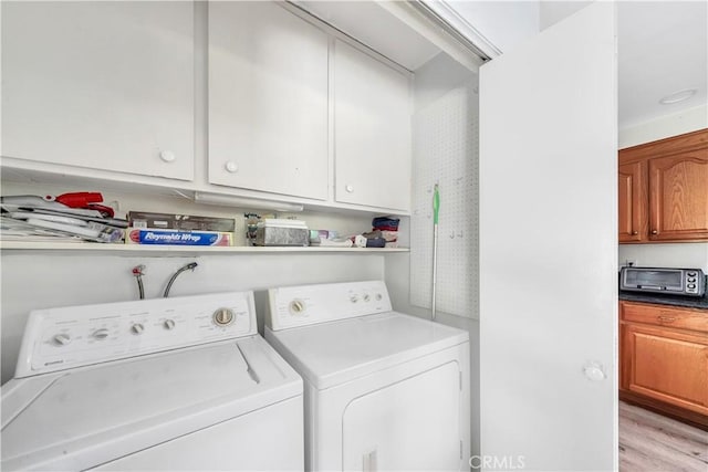 clothes washing area with light wood-type flooring, a toaster, and separate washer and dryer