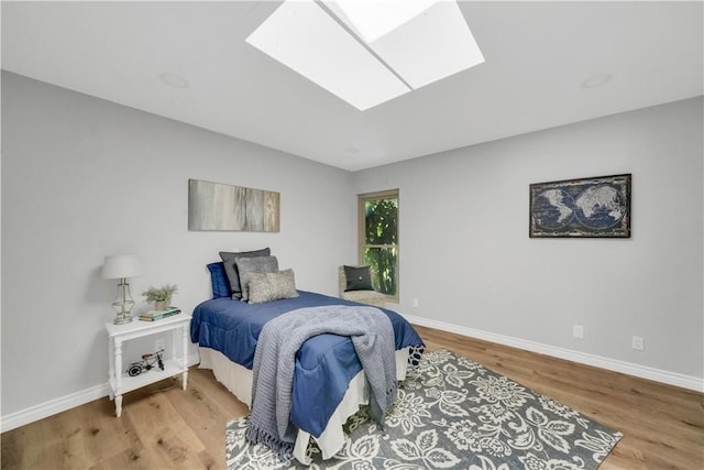 bedroom featuring a skylight and hardwood / wood-style flooring