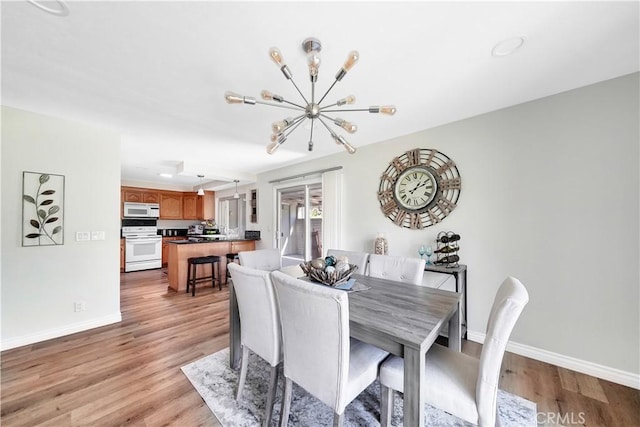 dining room featuring a notable chandelier, light wood-style flooring, and baseboards