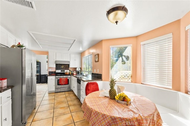 kitchen with appliances with stainless steel finishes, light tile patterned floors, white cabinetry, and sink