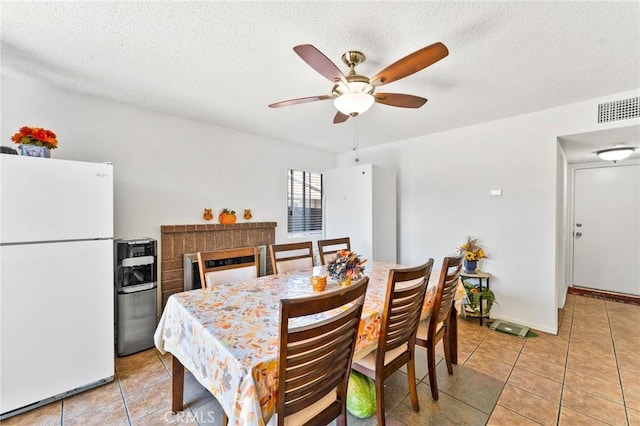 dining room featuring tile patterned flooring, ceiling fan, and a textured ceiling