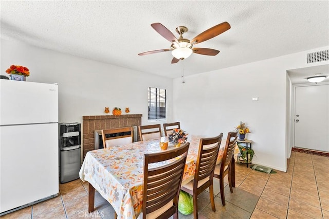 tiled dining area with ceiling fan and a textured ceiling