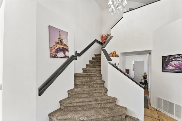 stairway with tile patterned flooring, a towering ceiling, and an inviting chandelier