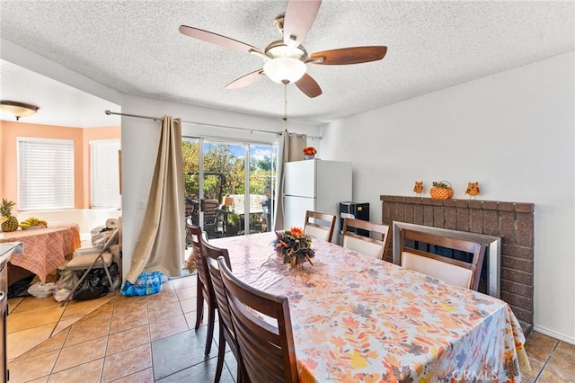 tiled dining room with ceiling fan and a textured ceiling