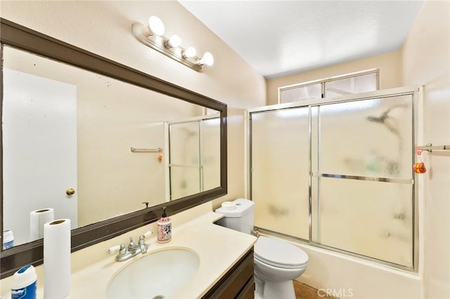 full bathroom with combined bath / shower with glass door, vanity, and toilet