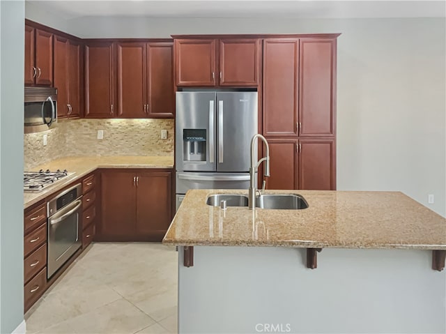 kitchen featuring tasteful backsplash, light stone counters, a breakfast bar area, appliances with stainless steel finishes, and sink