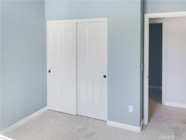 unfurnished bedroom with light carpet and a closet