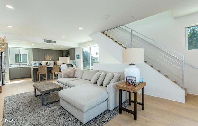 living area featuring visible vents, light wood finished floors, and plenty of natural light