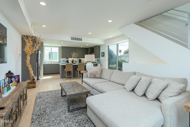 living room with recessed lighting, a wealth of natural light, light wood-type flooring, and visible vents