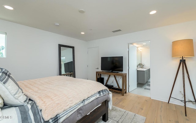 bedroom with connected bathroom and light hardwood / wood-style floors