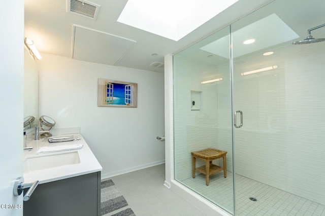 bathroom with vanity, walk in shower, a skylight, and tile patterned flooring