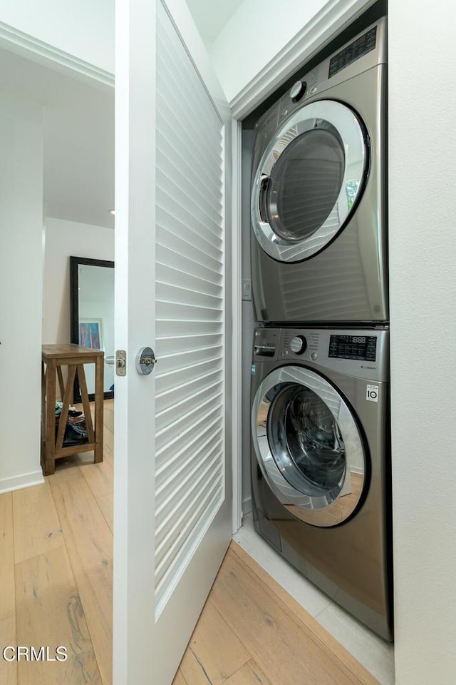 washroom featuring light wood-type flooring, laundry area, and stacked washing maching and dryer