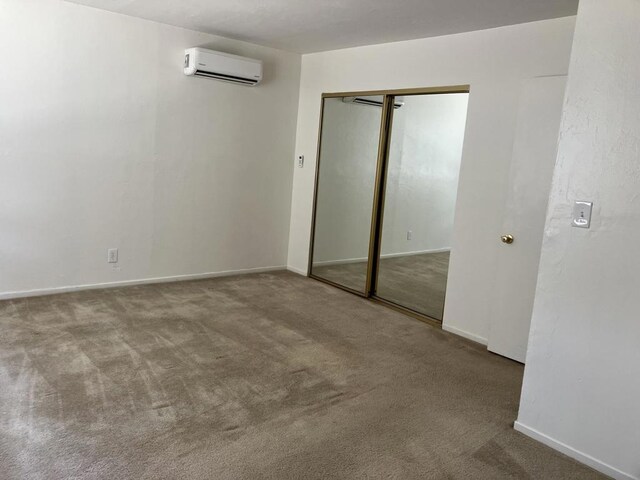 unfurnished bedroom with light colored carpet, an AC wall unit, and a closet